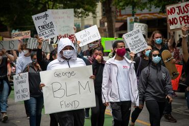 Diverse group protesting for Black Lives Matter with signs demanding justice and equality.