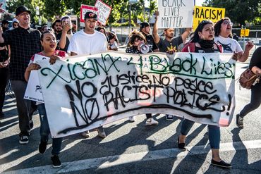 Protesters march with banners against racism and police violence.