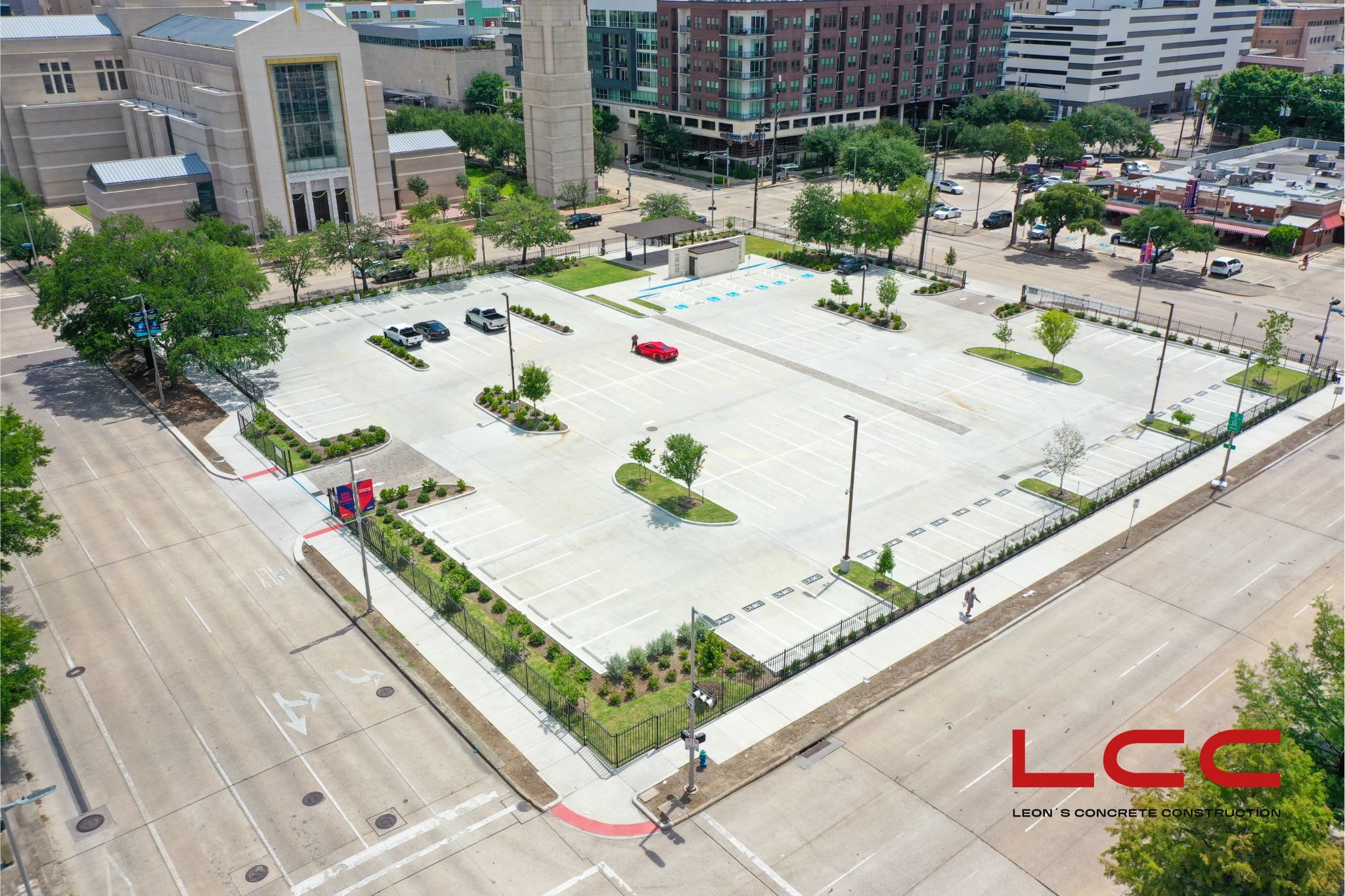 A mostly empty urban parking lot with a few cars and a church nearby.