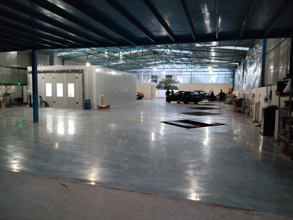 Spacious, well-lit automotive workshop with cars and work areas.