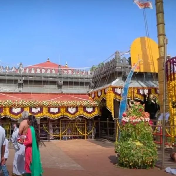 People gathered at a decorated temple courtyard under clear blue sky.