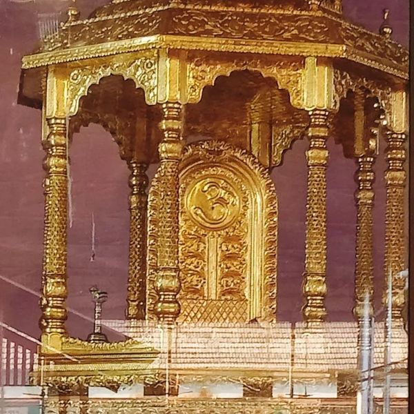 Ornate golden Hindu altar with Om symbol and intricate carvings.