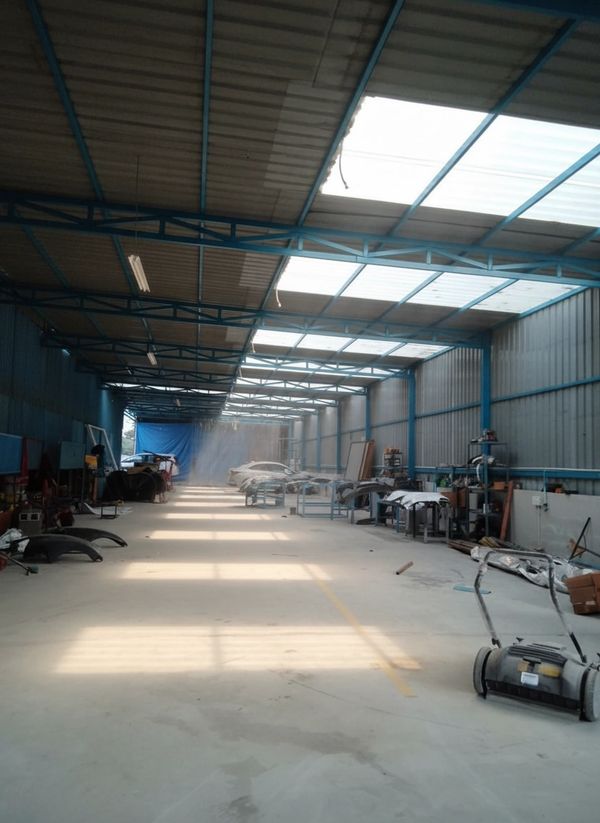 Spacious industrial workshop with blue metal framework and scattered equipment.