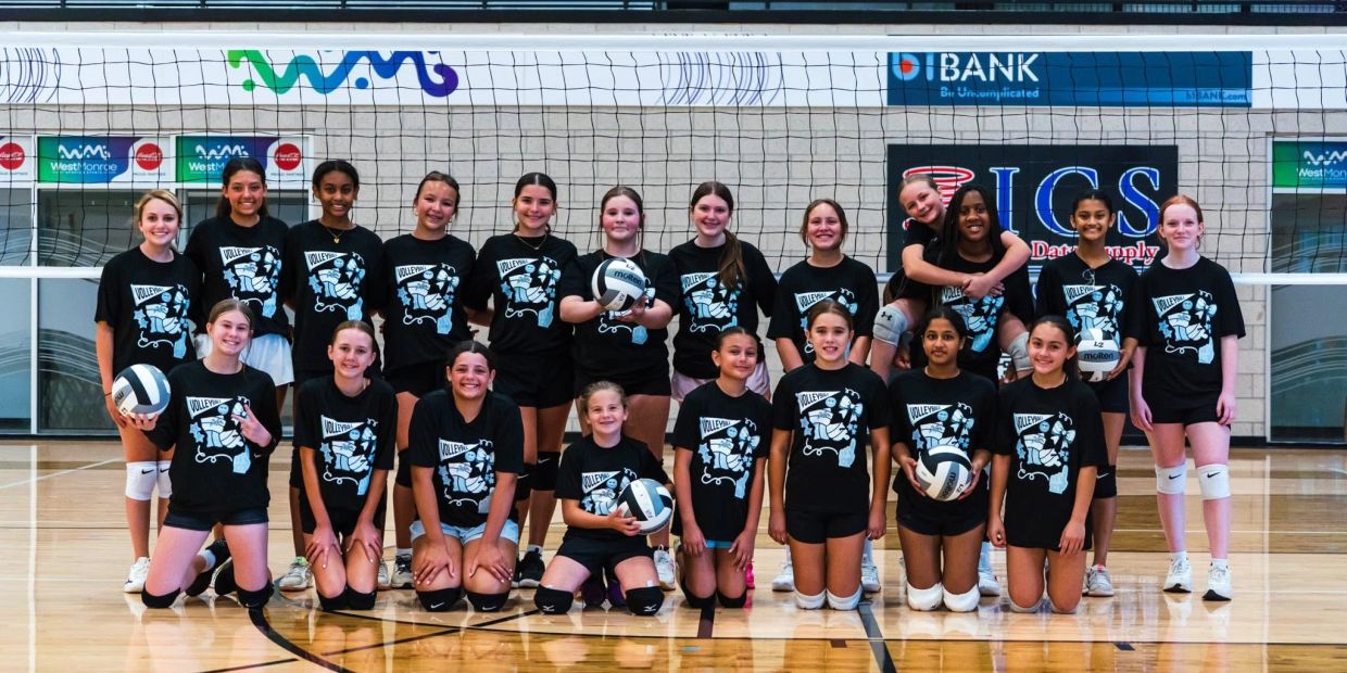 A girls' volleyball team posing on the court.