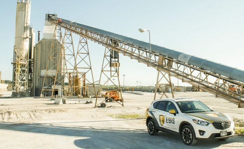 Security vehicle at an industrial site with conveyor belts.