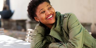 A woman smiling while resting her arms on a table