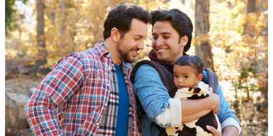 Men smiling while carrying a baby