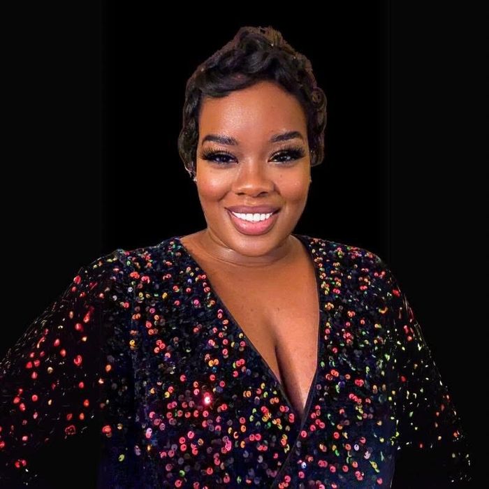 Smiling woman in a sparkling sequin dress against a black background.