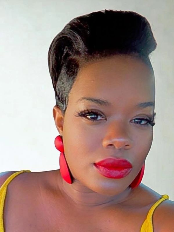 Woman with bold red lipstick and earrings in a yellow top.