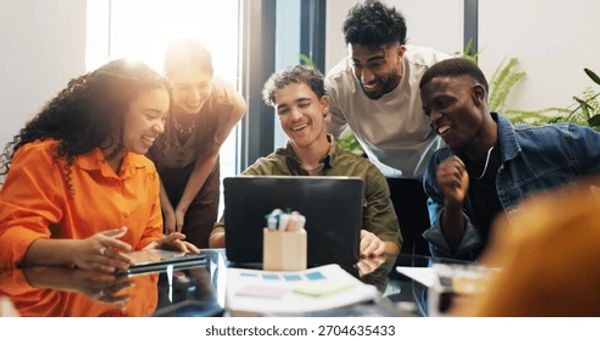 Group of young people happily collaborating around a laptop.