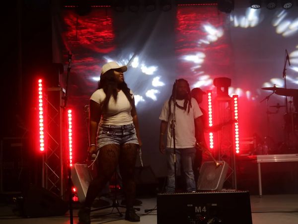Two performers on a stage with red and white lights.