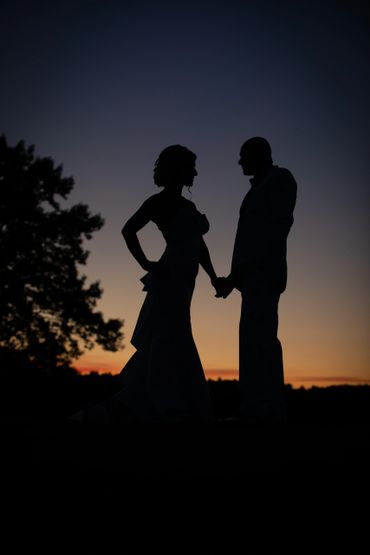 Silhouetted couple holding hands at sunset.