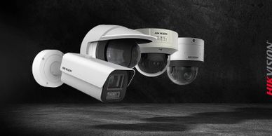 Three white Hikvision security cameras against a dark background.
