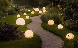 A winding garden path lit by glowing spherical lights at dusk.
