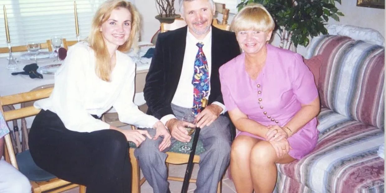 Three people sitting indoors, smiling at the camera, dressed in semi-formal attire.