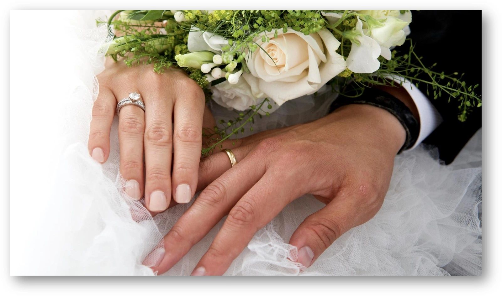 Wedding couple touching hands with rings and flowers.