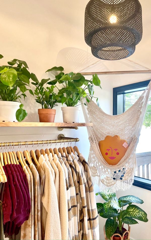 a hammock with a orange smiley face pillow and 3 plants.