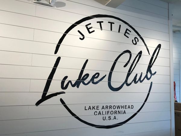 A white wall with jetties lake club logo