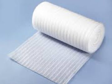 A rolled-up white foam mattress topper on a light surface.