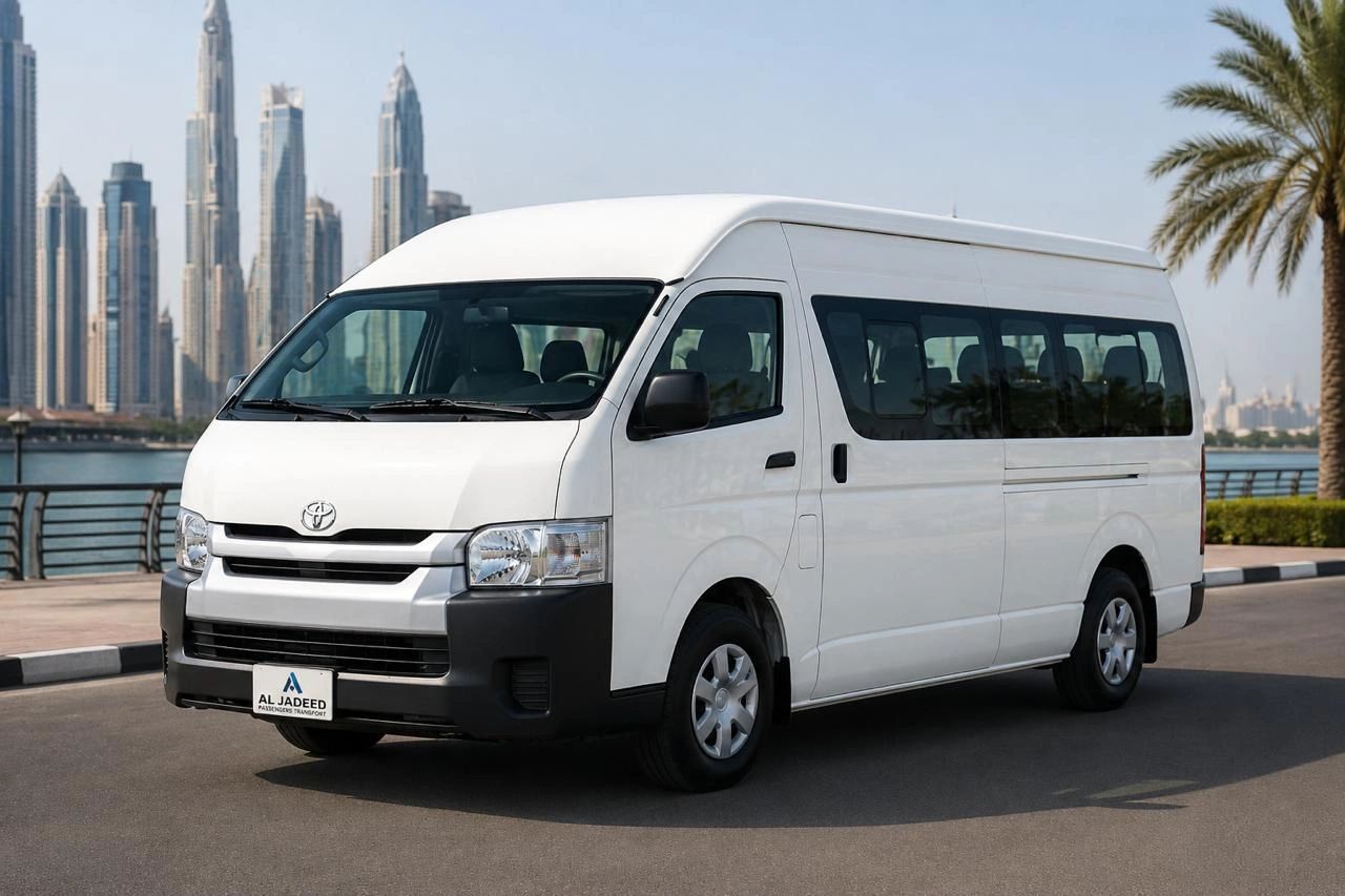 White Toyota passenger van parked by waterfront with city skyline in background.