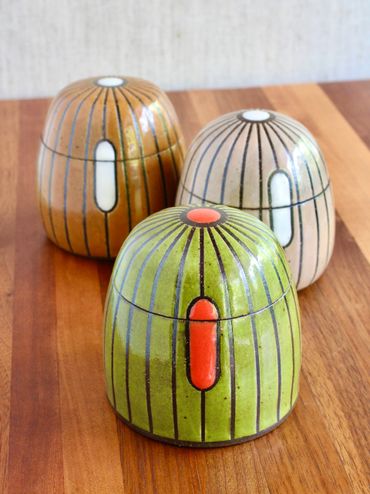 Three colorful ceramic containers with vertical stripes and oval accents.