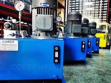 A row of blue industrial hydraulic power units with gauges and motors.