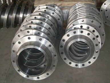 Stacks of shiny metal flanges with bolt holes, arranged in rows.