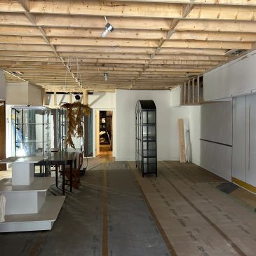Interior of a partially renovated room with exposed ceiling and display shelves.