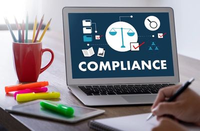 Laptop screen showing compliance concept with scales and check marks.