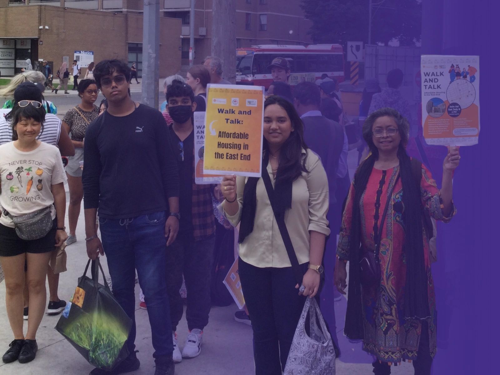 People holding signs about affordable housing at a community walk event.
