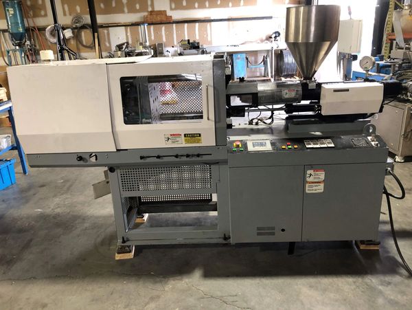 Industrial injection molding machine in a workshop setting.