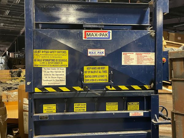 A blue MAX-PAK baler with multiple safety warning labels 