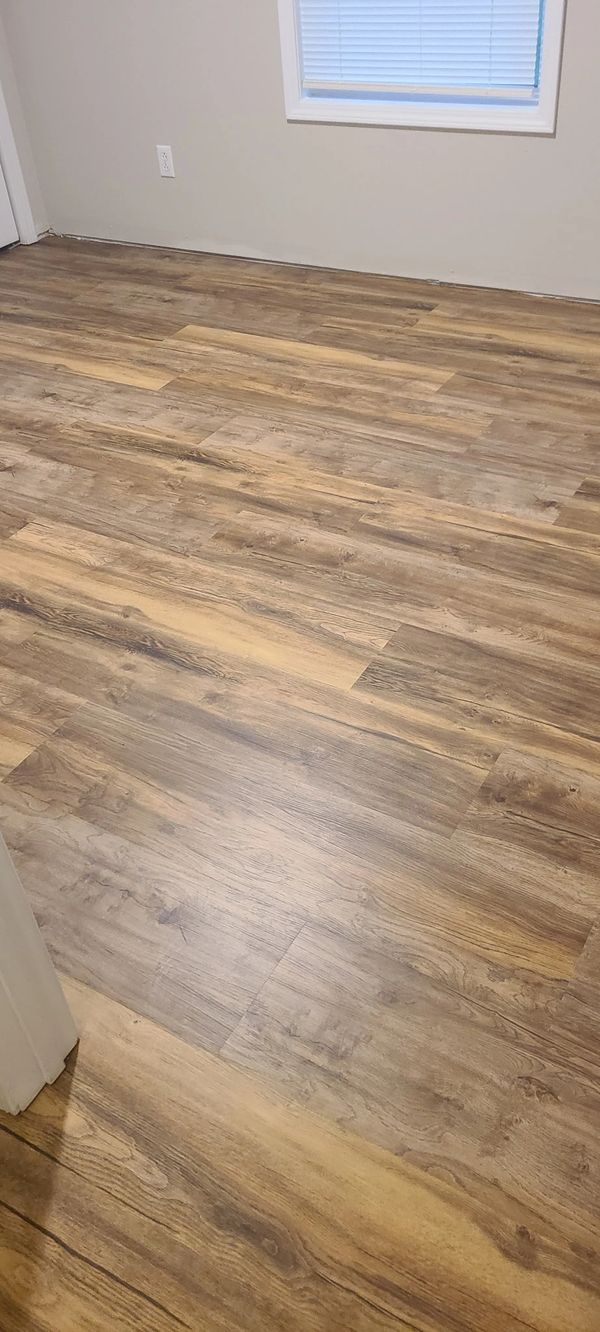 Newly installed wood-patterned vinyl flooring in a room with neutral walls.