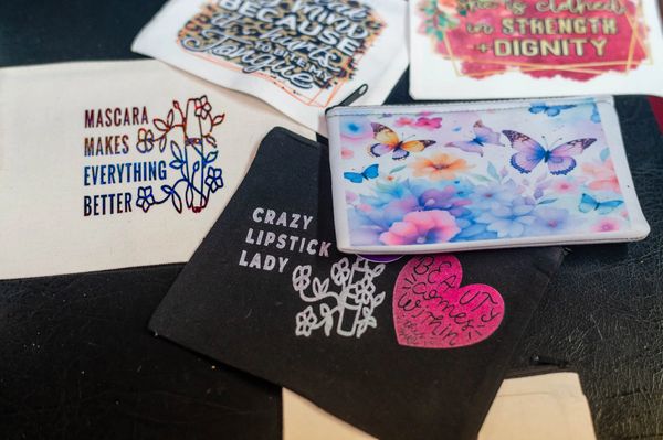 Assorted makeup bags with quotes like "Mascara makes everything better" and butterfly designs.