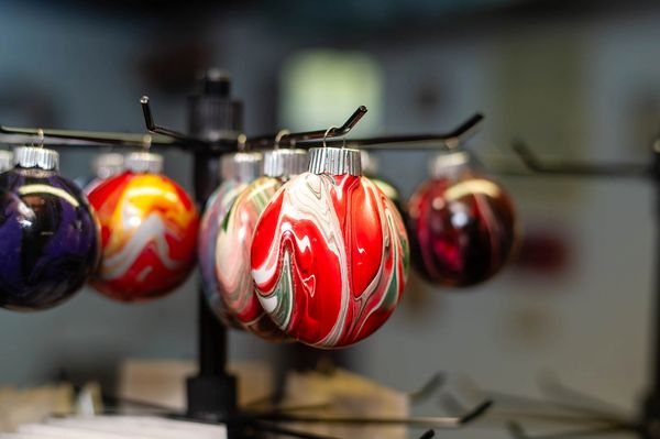 Handmade marbled Christmas ornaments on a display rack, festive holiday decor.