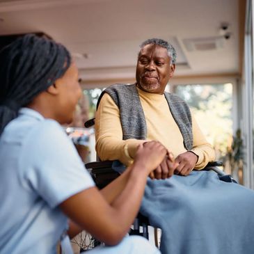Caregiver talking with an elderly man in a wheelchair