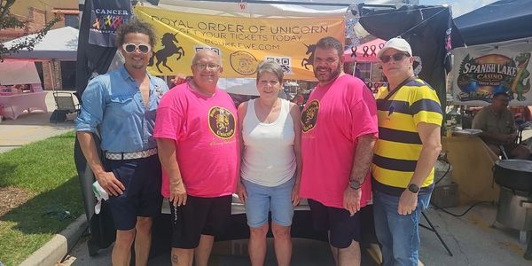 Group of five adults posing at an outdoor event booth.