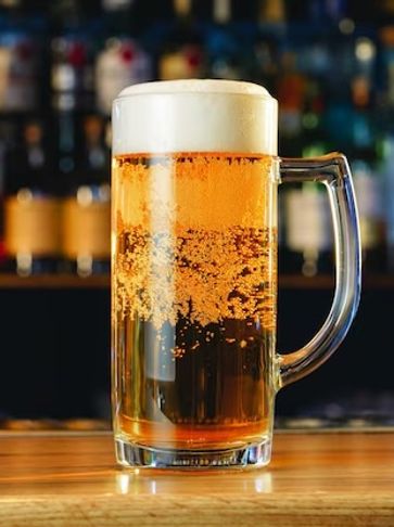 A frothy mug of beer on a wooden bar counter.