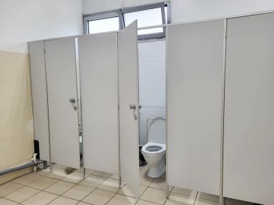 Bathroom stalls with one door open revealing a toilet.
