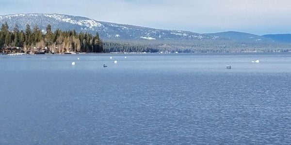 A scenic landscape featuring mountains, a river, and lush greenery under a clear blue sky.