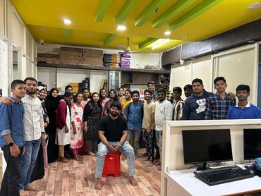 Group photo of young adults in a colorful room with computers.