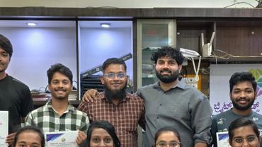 Group of young adults proudly displaying certificates in a classroom setting.