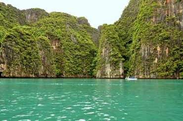 Clear turquoise water with tall limestone cliffs covered in greenery.