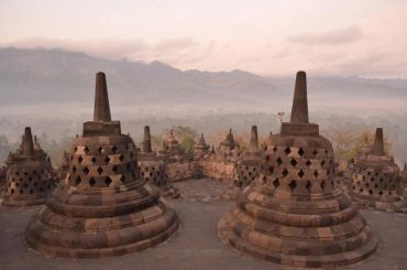 Ancient stone stupas at Borobudur temple at sunrise.