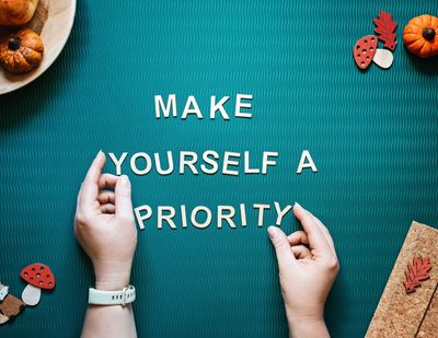 A pair of hands arranging letters to form a sentence saying, “make yourself a priority “