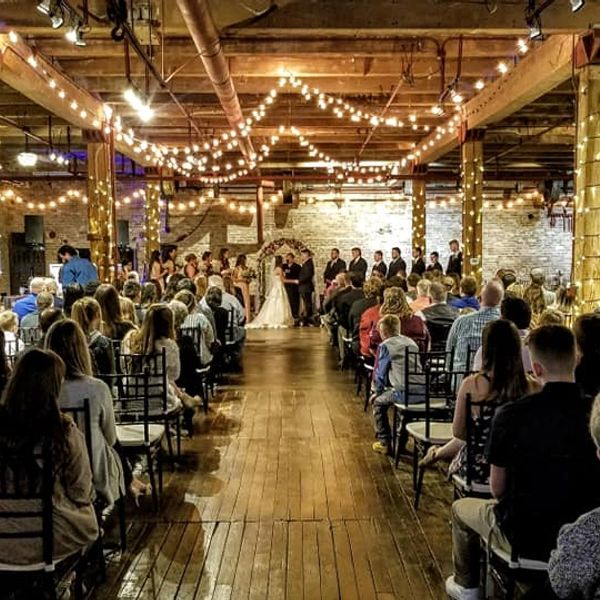 Indoor wedding ceremony with string lights and a seated audience.