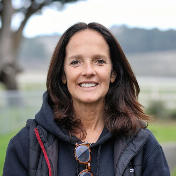 Smiling woman with dark hair outdoors in casual attire.