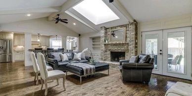 Spacious living room with vaulted ceiling, skylight, and brick fireplace.