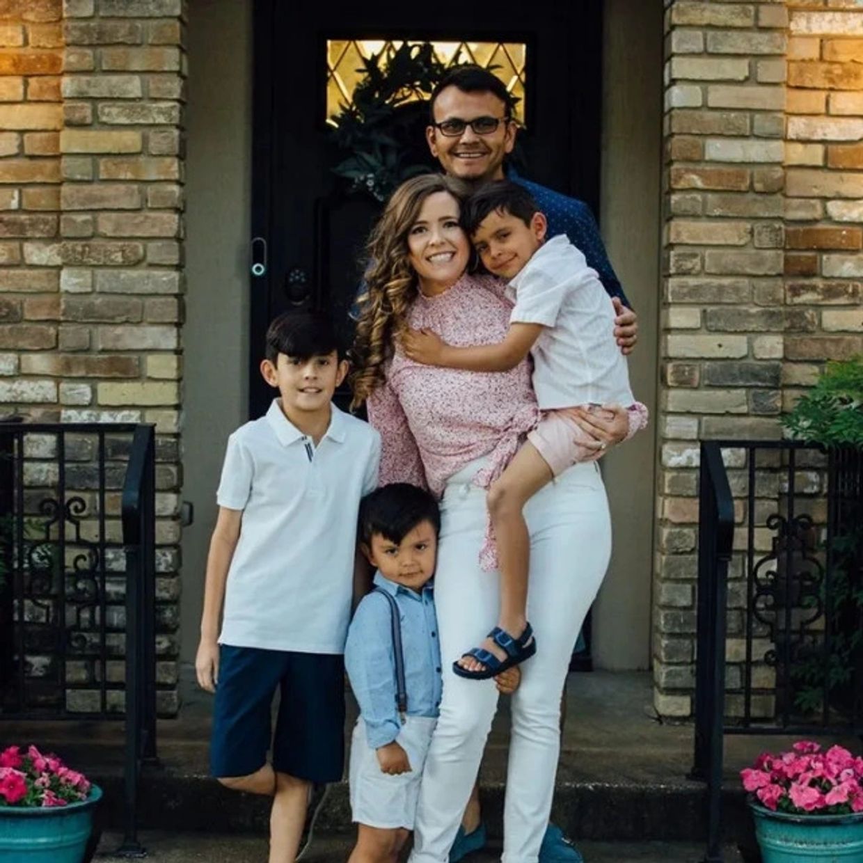 A happy family of five posing in front of their home.