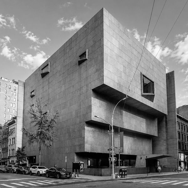 A modern, geometric building with angular windows in an urban setting.